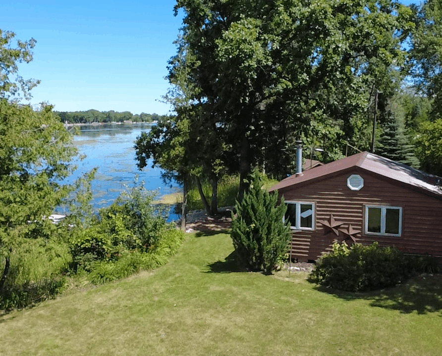 A cozy lakeside cottage nestled along the shoreline, surrounded by peaceful trees