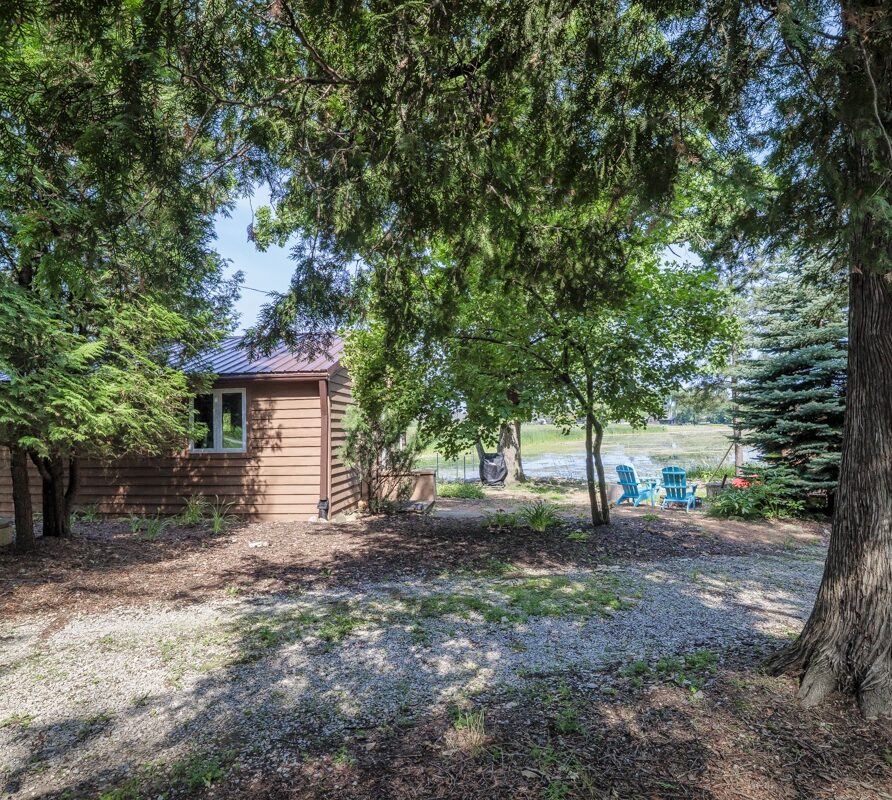 View of the cottage with outdoor seating and fire pit by the water