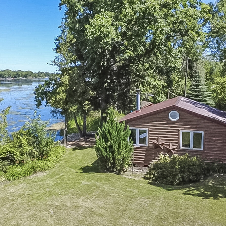 A cozy lakeside cottage nestled along the shoreline, surrounded by peaceful trees